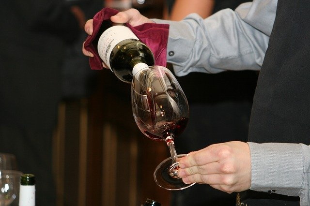 Sommelier pouring red wine into a glass.